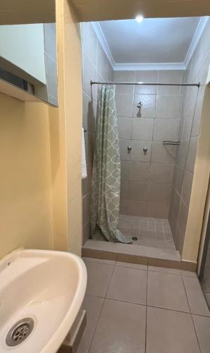 a bathroom with a shower and a sink at Dube Villa in KwaDukuza