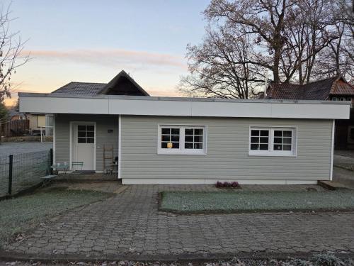 Cozy Luhe Cottage في بيسبينغين: منزل أبيض صغير على ممر من الطوب