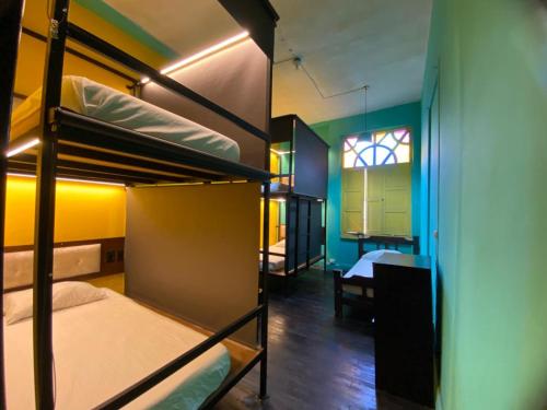 two bunk beds in a room with a table and a window at Casona Don Juan Hostel in San Gil