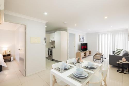 a white living room with a white table and chairs at Smart Suites Self Check-in Apartments - Rocklea Station N in Brisbane