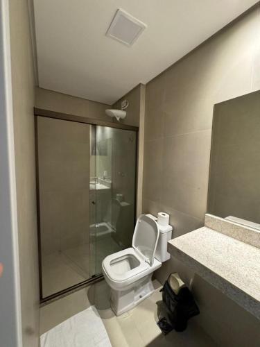 a bathroom with a toilet and a glass shower at Flat Garden Frances in Marechal Deodoro