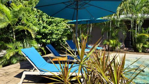 タマリンドにあるTee-K Lodge Tamarindoの- プールサイドの青い椅子2脚とパラソル1本