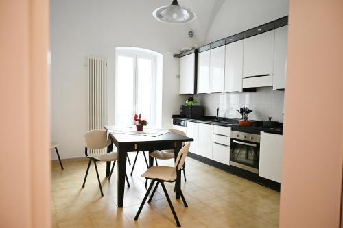 a kitchen with white cabinets and a table and chairs at A Casa di Nonna Nunzia - Centro di Gravina - 20min da Matera in Gravina in Puglia