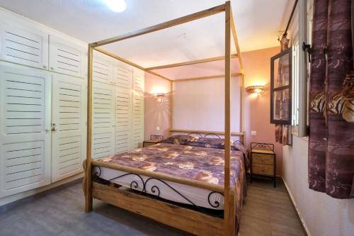 NianingVILLA PAULINE Nianing2的一间配有四柱床和白色百叶窗的卧室