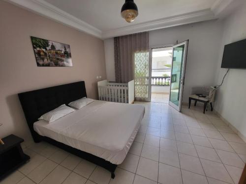 a bedroom with a bed and a sliding glass door at Duplex el 3ebdelleyya en face tennis club la marsa in Tunis