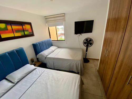 a room with two beds and a flat screen tv at Apartamento con piscinas y jacuzzi in La Tebaida