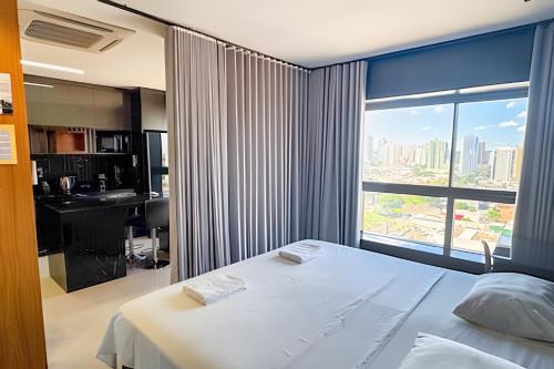 ein Schlafzimmer mit einem weißen Bett und einem großen Fenster in der Unterkunft High Luxury Geta on the 18th Floor Vertigo Studios in Campo Grande