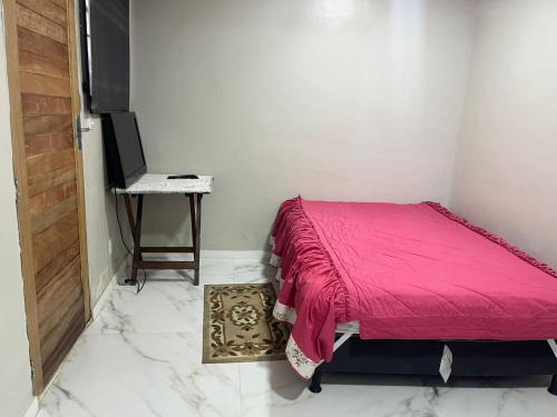 a bedroom with a bed and a table with a laptop at Casa do Alessandro in Vila Velha