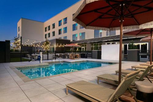 a swimming pool with chairs and an umbrella at The Elmore Hotel, DFW Southlake, a Tribute Portfolio Hotel in Southlake