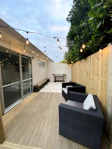 a patio with two couches on a wooden deck at The Sugar shack in Tauranga
