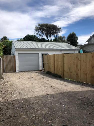 a garage with a fence in front of a house at The Sugar shack in Tauranga