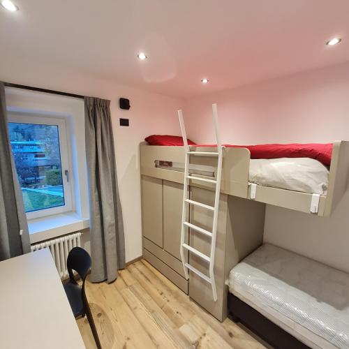 a room with two bunk beds and a desk at Residenza Andreotti in Ossana