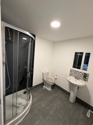 Un baño con ducha, inodoro y lavabo. en TBH Hotel, en Barking