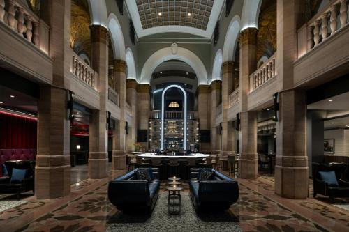 a large lobby with a bar in the middle at THE MIDLAND HOTEL, Chicago, a Tribute Portfolio Hotel in Chicago