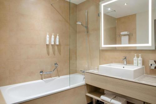 Un baño con bañera, lavabo y espejo. en Courtyard by Marriott Bremen, en Bremen