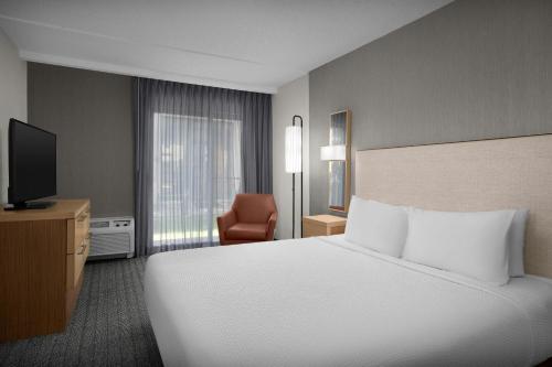 Courtyard by Marriott Dallas DFW Airport North/Irving في ايرفينغ: غرفة فندق مع سرير وتلفزيون