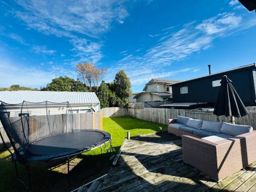 a patio with a couch and an umbrella at Seaside heaven family friendly in Tauranga