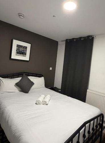 a bedroom with a bed with two slippers on it at TBH Hotel in Barking