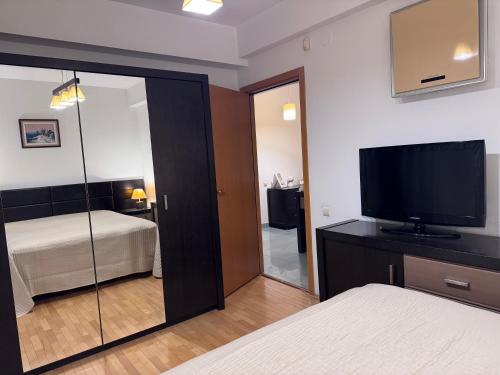 a hotel room with a television and a bedroom at La Residenza in Craiova
