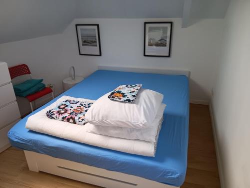 a blue bed with pillows on it in a room at Un nid cosy sous les toits in Cancale