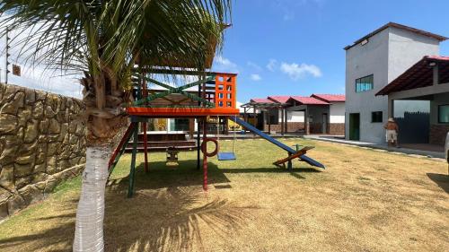 un parco giochi con scivolo accanto a una palma di Chalés do Atlântico a Salinópolis