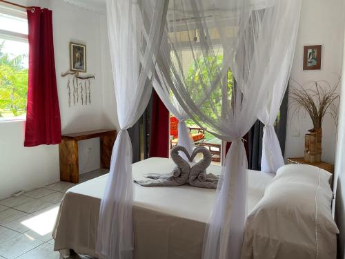 una camera da letto con un letto con tende bianche di Fare ATAROA a Te-Fare-Arii