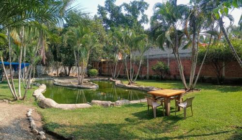a table and chairs in a yard with a pond at Lago24 Habitaciones in Cocoyoc