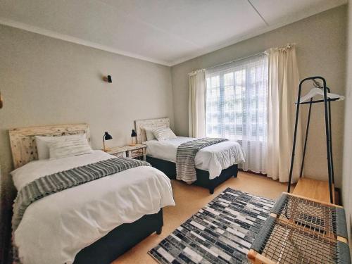 a bedroom with two beds and a window at Swannie Creek private nature retreat with hot tub and fireplace in Grabouw