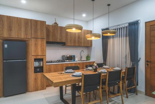 a kitchen and dining room with a table and a refrigerator at Villa Kusuma 3 Seminyak in Badung