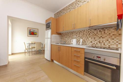 a kitchen with wooden cabinets and a table in the background at B81 - Casa do Outeiro Westcoast Home in Vila do Bispo