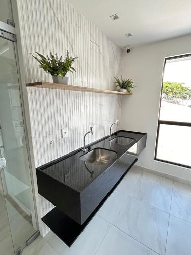 a bathroom with a sink in a black counter at Melhores Flats - Elegante a 5 min do mar de Tambaú in João Pessoa