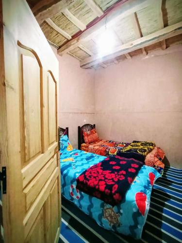 a bedroom with two beds in it with a bedskirts at Auberge le calme restaurante in Bou Drarar
