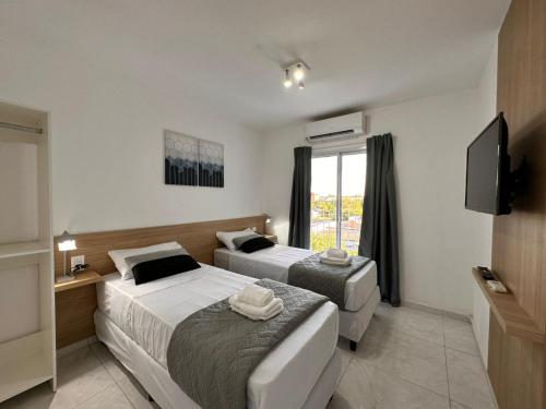 2 letti in camera d'albergo con televisore di Vela Villa Apart a Villa Ángela