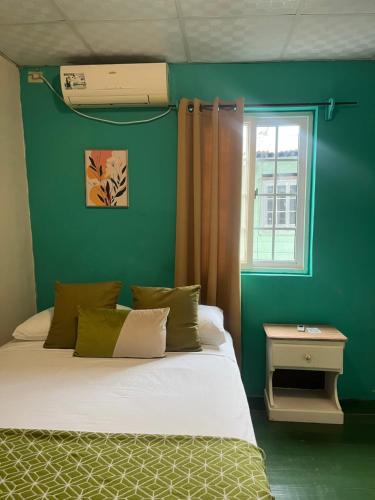 una camera da letto verde con un letto e una finestra di Hostal Cay a Bastimentos