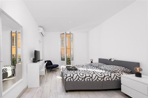 um quarto branco com uma cama e uma tv em 3P Monaco avec parking em Saint-Antoine