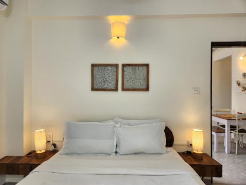 Premium 1BHK Beachside Apartment - Pool, Full Kitchen & Balcony, Candolim في كاندوليم: غرفة نوم بسرير مع شراشف بيضاء ومصباحين