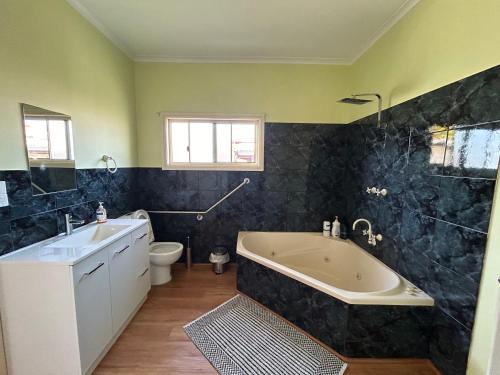 un bagno con vasca, WC e lavandino di Spacious Stylish Coastal Escape a Tuncurry