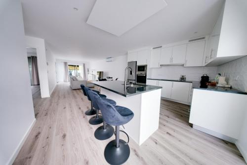 een keuken met witte kasten, een aanrecht en stoelen bij C&A Guest House in Furnas