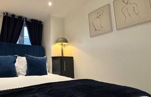 ein Schlafzimmer mit einem Bett mit blauen Kissen und einer Lampe in der Unterkunft The Foundry by The Hive WA1 Funky Spacious 1 Bed King Apartment in Warrington