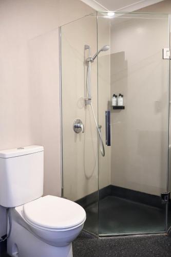 a bathroom with a toilet and a glass shower at Noa Hotel in Auckland