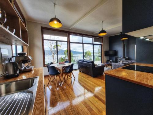 a kitchen and living room with a table and chairs at The Beach House- private jacuzzi and wood fire! in Dover