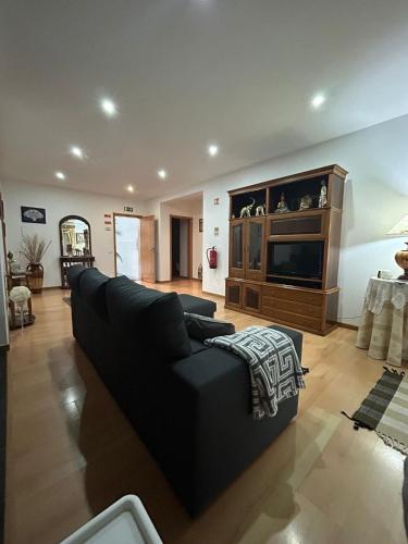 a living room with a black couch and a tv at Alojamento Luna in Porto Judeu