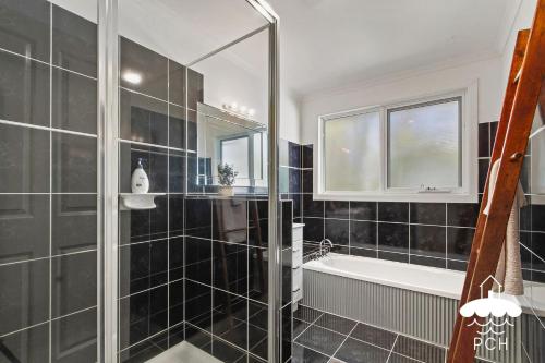 a bathroom with black tiled walls and a bath tub at Wyrallah House - Stay 5 Nights PAY 4 - Jan 1-22 in Lakes Entrance