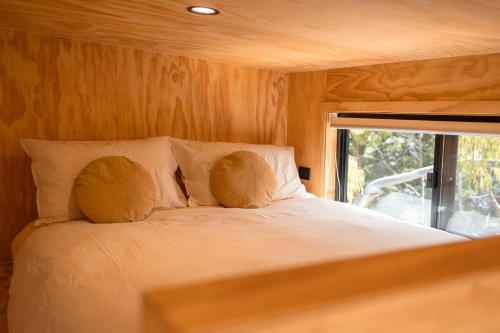 a bedroom with a bed with two pillows and a window at Whittle Home - NEW TINY HOME in Robe