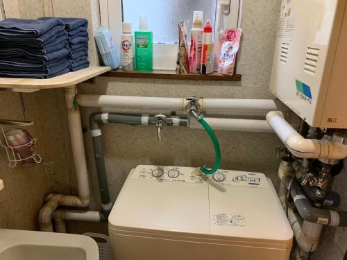 a bathroom with a toilet with a green hose at 釧路の夕日に近い宿トラベラーズイン南大通 in Kushiro
