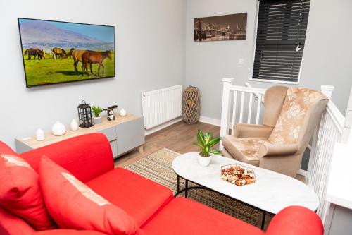 a living room with a red couch and a table at Parador Villa in Stockport