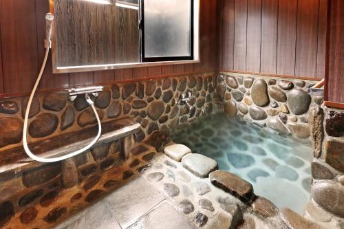 een badkamer met douche met een stenen muur bij 旅館 家族湯 いまむら in Yamaga