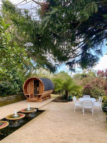 a wooden sauna with a table and chairs in a garden at Tulip Gardens Estate - Spa, Sauna & Pet Friendly in Springbrook