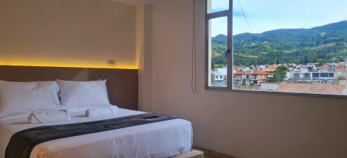 a bedroom with a bed with a large window at Posada Pa'sumerce in Tibasosa