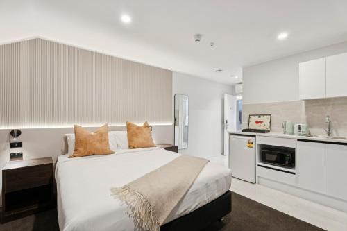 a white bedroom with a bed and a kitchen at Sai Motels - Greenlane Auckland in Auckland